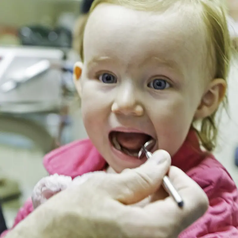 Niña pequeña con la boca abierta durante su primera revisión dental